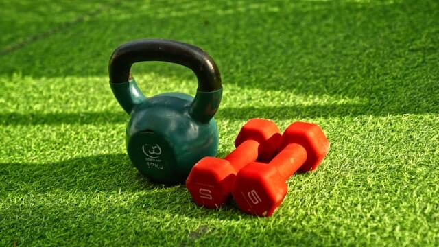 Fitness equipment with kettlebell and dumbbells on green turf